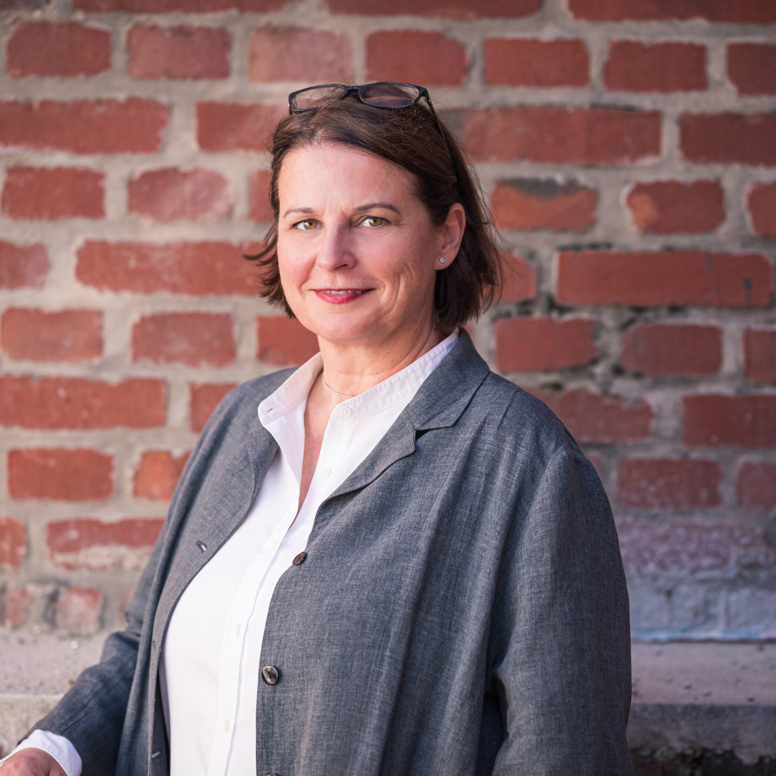 Portraitfoto von Yvonne Friedland vor einer Backsteinmauer
